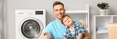 Father and son sitting on the floor doing laundry 