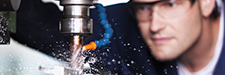 Close up of worker with safety glasses at milling machine in workshop.