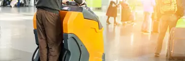 Man driving professional floor cleaning machine at airport or railway station. Floor care and cleaning service agency.