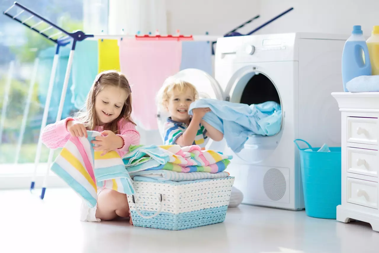 Kinder in der Waschküche helfen bei der Wäsche