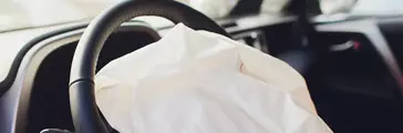 Interior of a automobile or car involved in a vehicle crash with a deployed steering column airbag