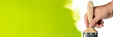 Hand using paintbrush with green Paint on wall