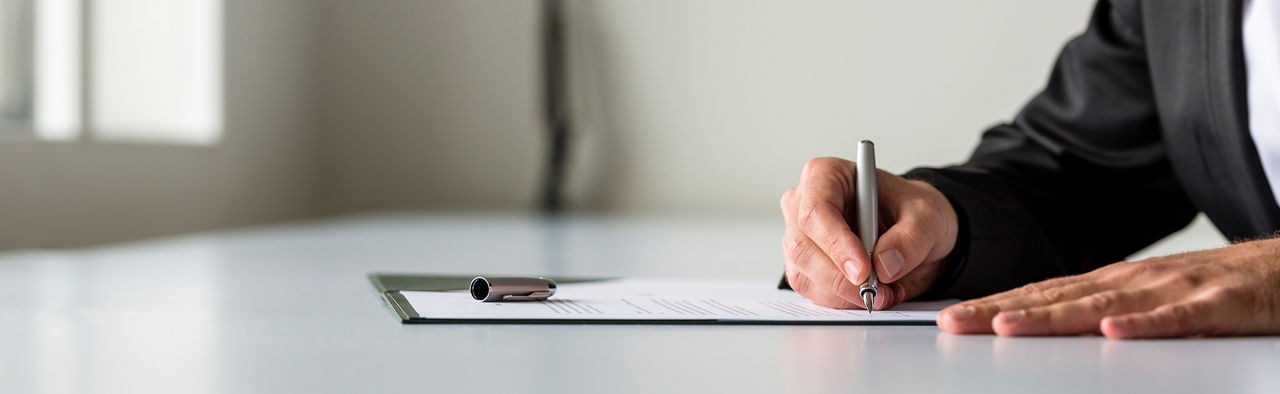 Hands signing a document