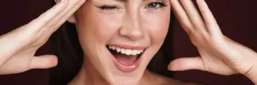 Image of smiling half-naked woman touching her temples and winking isolated over dark red background